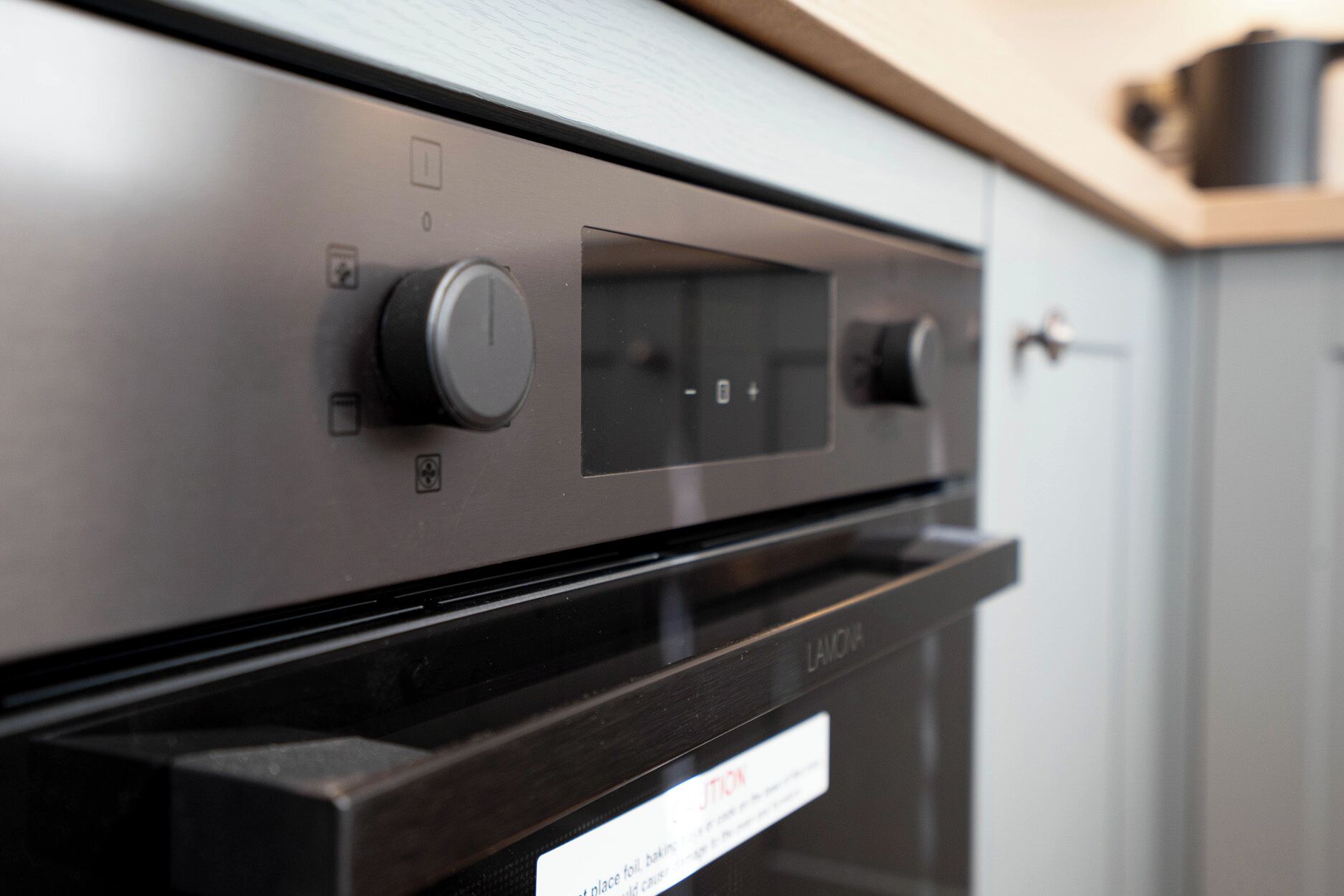 A kitchen with a stainless steel range hood, a control panel with knobs, and a label on the oven door.
