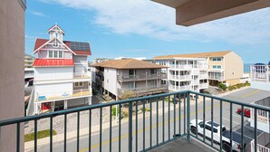 A multi-story building with balconies, a red-roofed structure, and a parking area with cars.