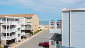 A beachfront hotel with multiple balconies, a parking area, and a view of the ocean.