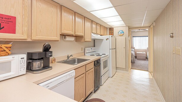 A compact kitchen with a microwave, coffee maker, sink, dishwasher, stove, and refrigerator.