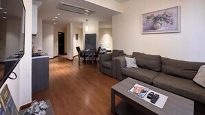 A modern living room with a sofa, coffee table, and a dining area with chairs and a table.