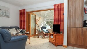 Ein Wohnzimmer mit einem blauen Sofa, einem Holzschrank und einem Fernseher.