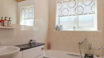 Une salle de bain moderne avec une baignoire, un lavabo et une fenêtre ornée d’un motif circulaire.