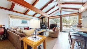 A cozy living room with a fireplace, comfortable seating, a television, and a balcony with outdoor seating.