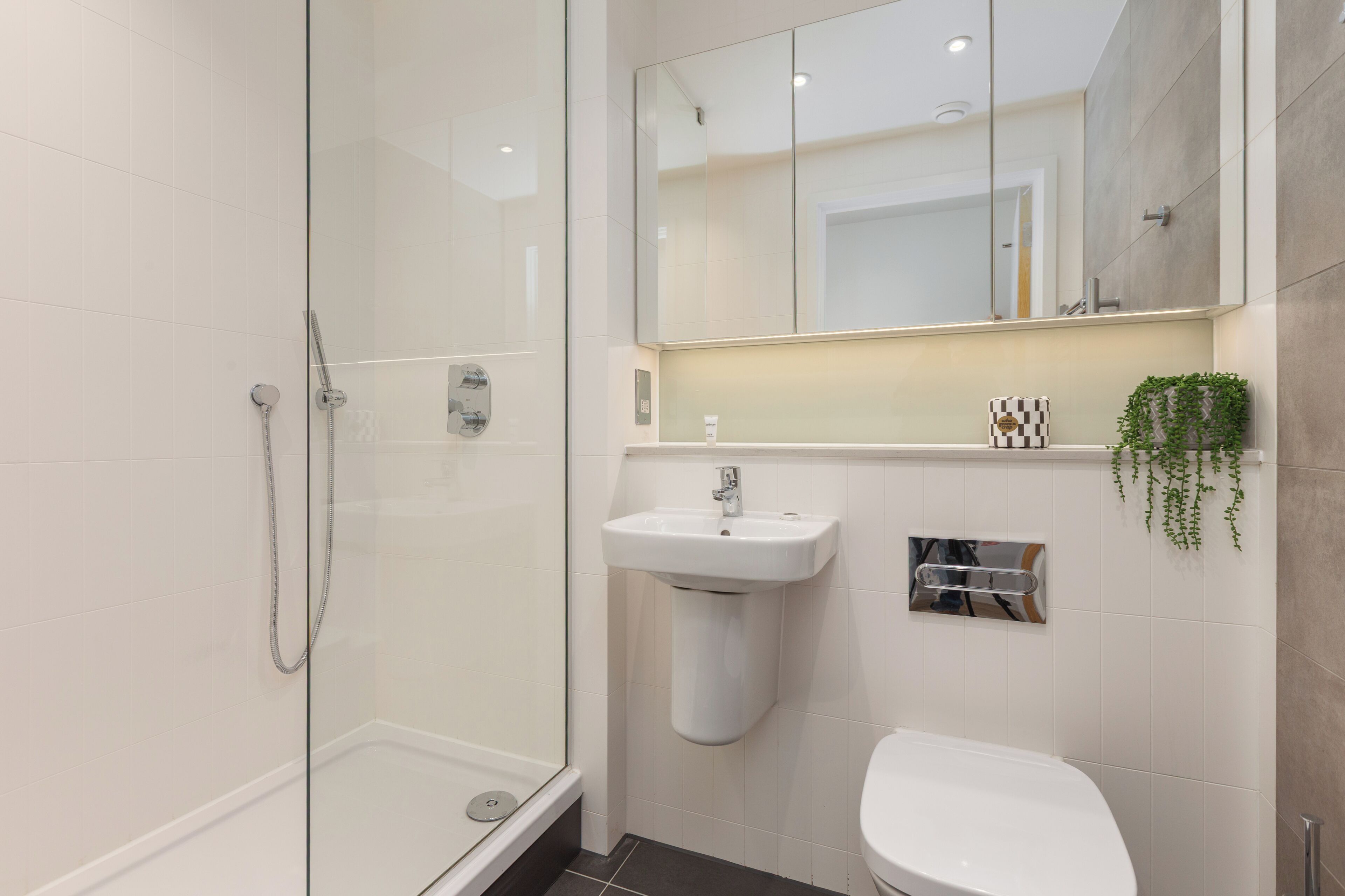 Un bagno moderno con box doccia in vetro, lavabo su piedistallo e servizi igienici.