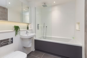 A modern bathroom with a glass-enclosed shower, a white sink, and a toilet.