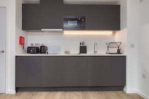 Una cucina moderna con mobili scuri, un forno a microonde, una macchina per il caffè e un lavello.