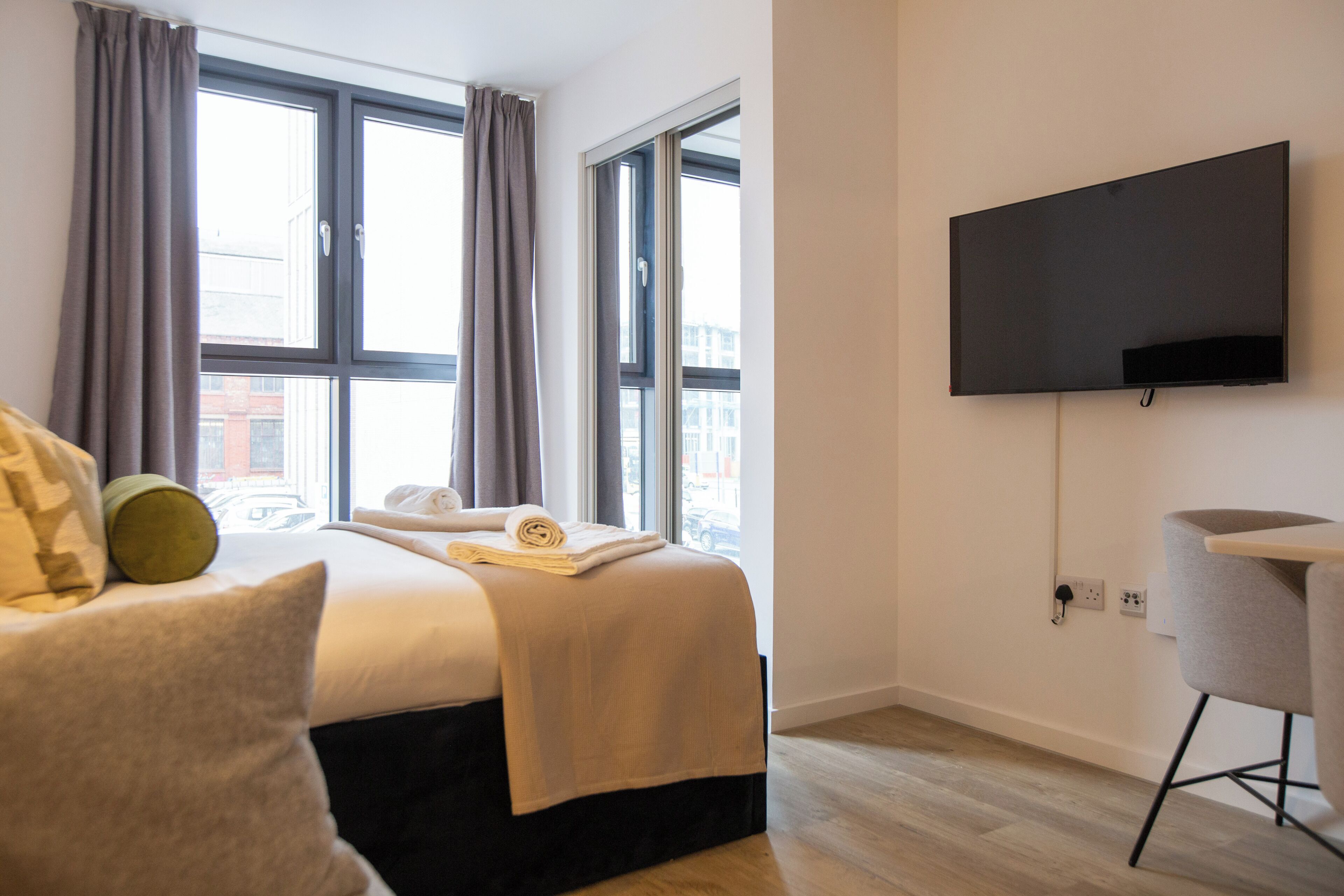 Une chambre d’hôtel avec un lit, une télévision et une fenêtre avec des rideaux.