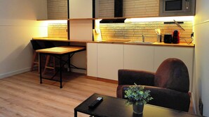 A compact kitchen with a microwave, toaster, and sink. There is a dining area with a table and chairs. - LOFT MADRID (Madrid)