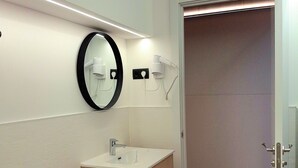 A modern bathroom with a toilet, sink, and mirror. - LOFT MADRID (Madrid)