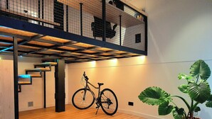 A modern interior with a wooden floor, a bicycle, and a large potted plant. - LOFT MADRID (Madrid)