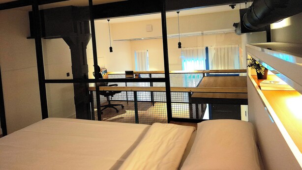 A hotel room with a bunk bed, a desk with a chair, a small table, and a potted plant. - LOFT MADRID (Madrid)