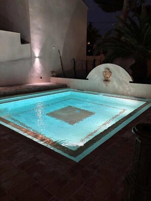 A rectangular pool with a geometric design, surrounded by a low wall and a small step leading into the water.