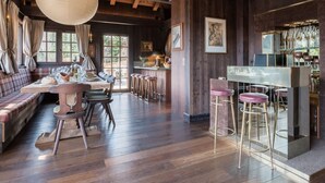 Un coin repas chaleureux avec une table en bois, des chaises et un comptoir de bar avec des tabourets.