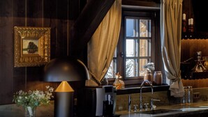 Une cuisine rustique avec des poutres en bois, un coin bar avec des tabourets et une fenêtre avec des rideaux.