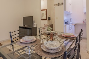 A dining area with a glass table, metal chairs, and a kitchen in the background. - Le Foyer du Bizet in Lierna (Lierna)