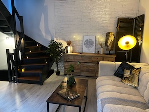 Un salon moderne avec un escalier, un canapé, une table basse et une lampe.
