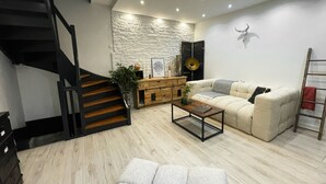 Una sala de estar moderna con una escalera, un sofá, una mesa de centro y un elemento decorativo en la pared.