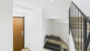 Un escalier avec une rampe en métal, une porte en bois et un mur blanc.