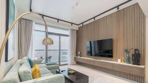 Un salon moderne doté d’un grand téléviseur à écran plat, d’un canapé, d’une table basse et offrant une vue sur la ville grâce à de grandes fenêtres.