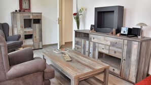 Una sala de estar con un sofá, una mesa de centro, un televisor y un mueble con cajones.