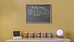 A wooden table with jars of coffee, a sign reading "Proudly Serving NORD DAGGIOS COFFEE", and two wooden buckets. - Joplin Avenue Junction: Two Bedroom Duplex (Tulsa)