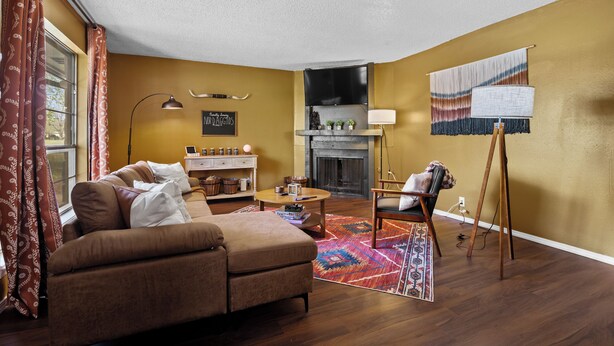 A living room with a sofa, a fireplace, a television, and a patterned rug. - Joplin Avenue Junction: Two Bedroom Duplex (Tulsa)