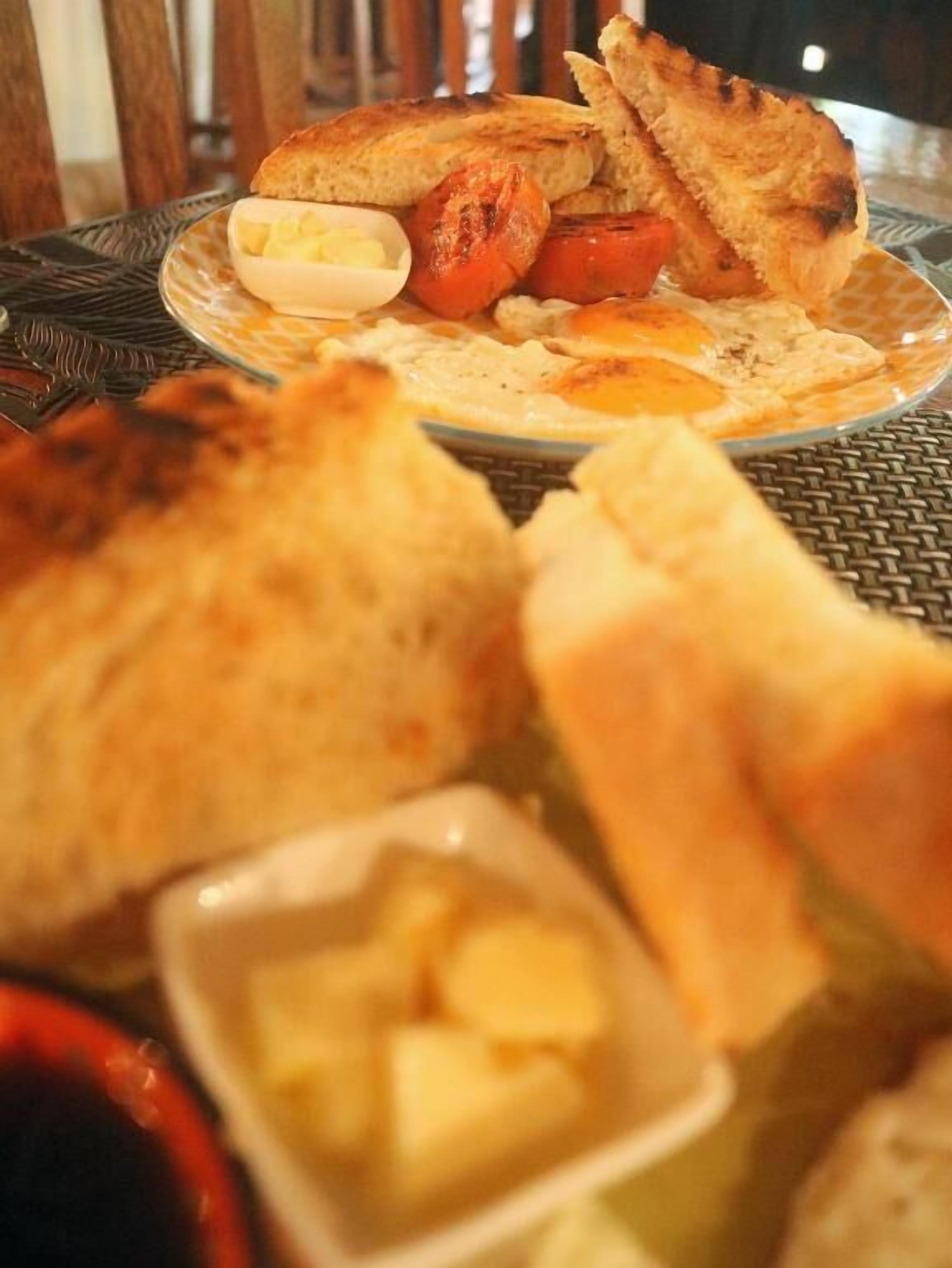 A breakfast plate with eggs, tomatoes, toast, and butter.