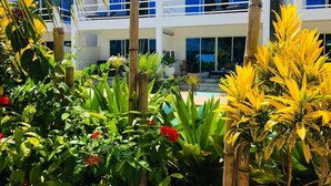 A modern two-story building with large windows and a pool in the background. - Aurora Boutique Hotel (Jambiani)