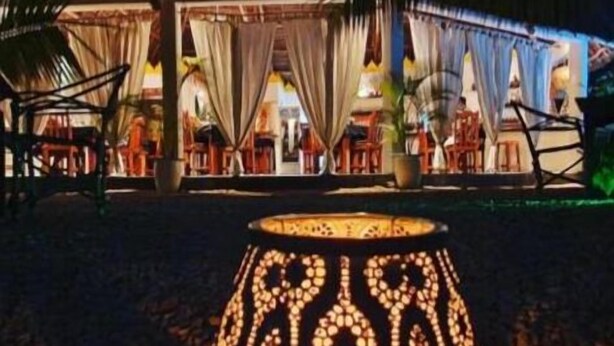 A night scene of a resort with a lit decorative lamp in the foreground. - Aurora Boutique Hotel (Jambiani)