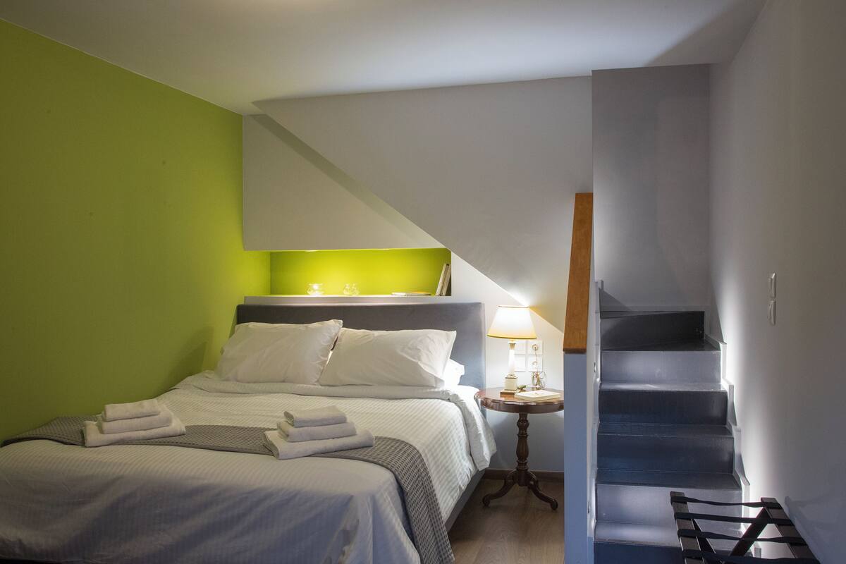 Ein Hotelzimmer mit einem Bett, einem Nachttisch und einer Treppe.