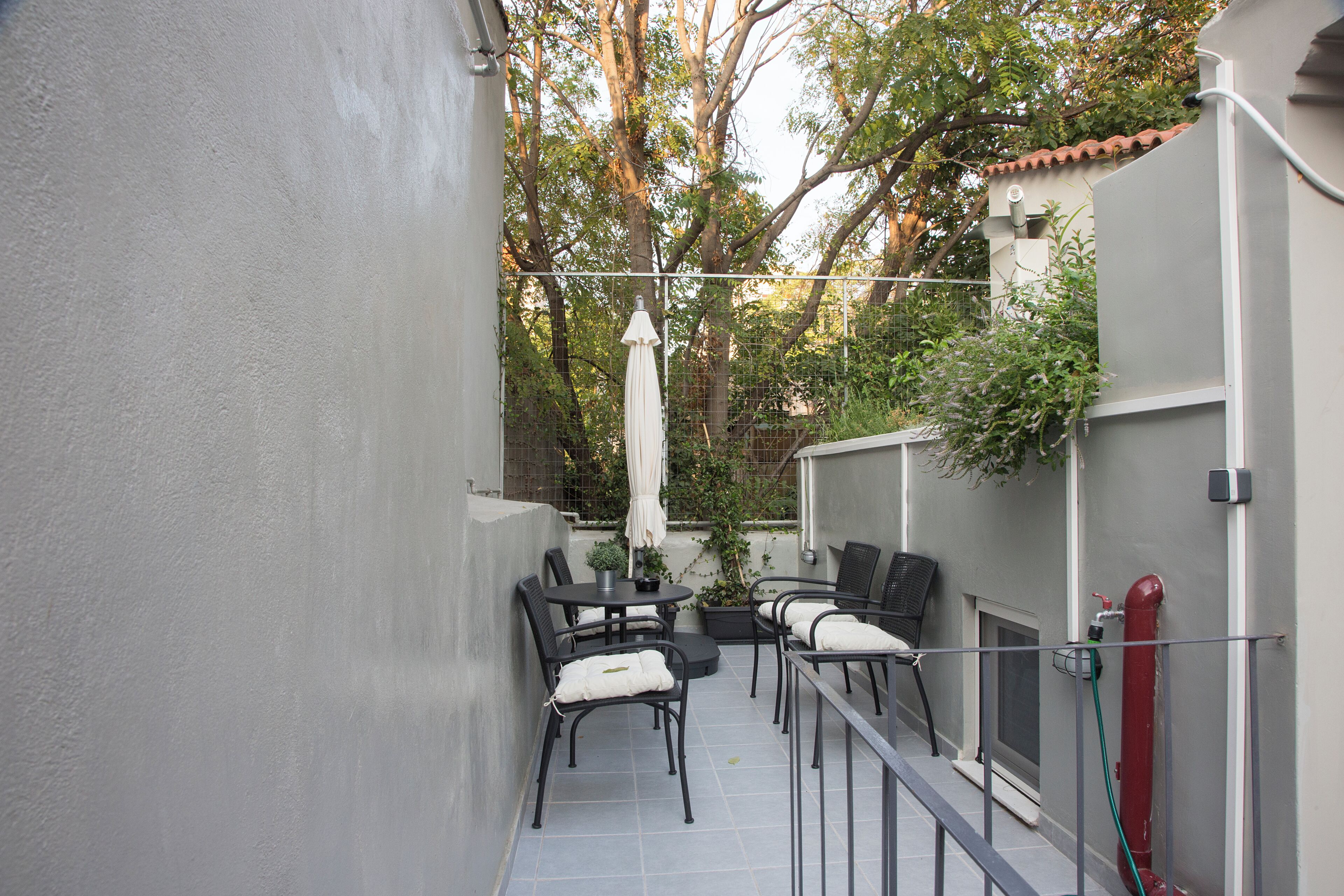 Un patio con una mesa y sillas, una sombrilla blanca y un hidrante rojo.