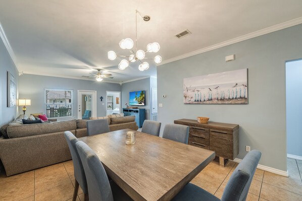 Un coin repas avec une table et des chaises en bois, un canapé et un tableau accroché au mur.
