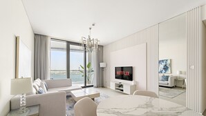 Une chambre d’hôtel moderne dotée d’une grande fenêtre, d’un téléviseur à écran plat, d’un coin repas et d’un canapé.