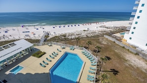 Un hotel con piscina, vistas a la playa y sillas de playa.