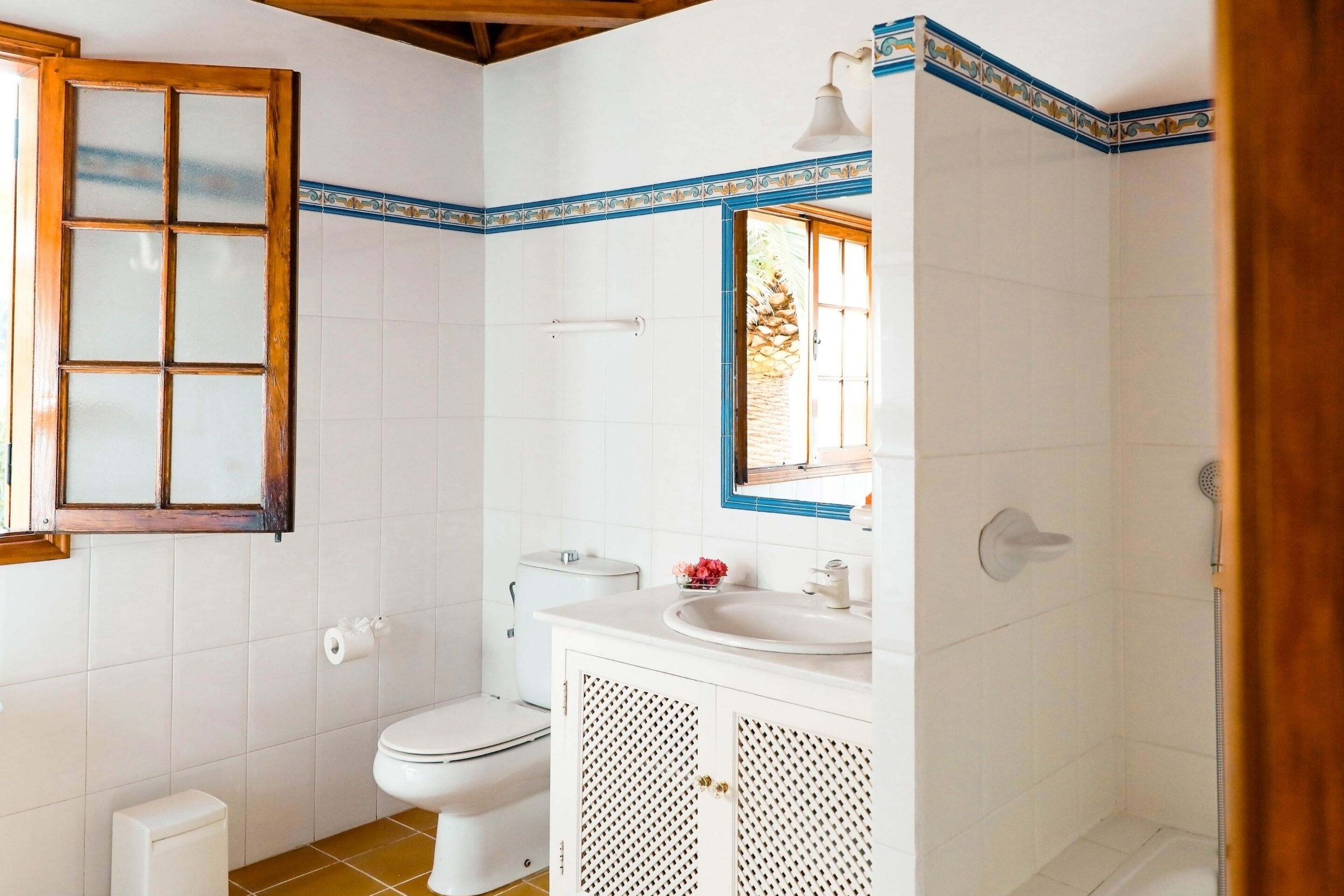 Une salle de bain avec des carreaux blancs, des toilettes, un lavabo et une douche.