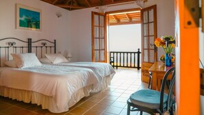 Un dormitorio con dos camas, un balcón y zona de comedor.