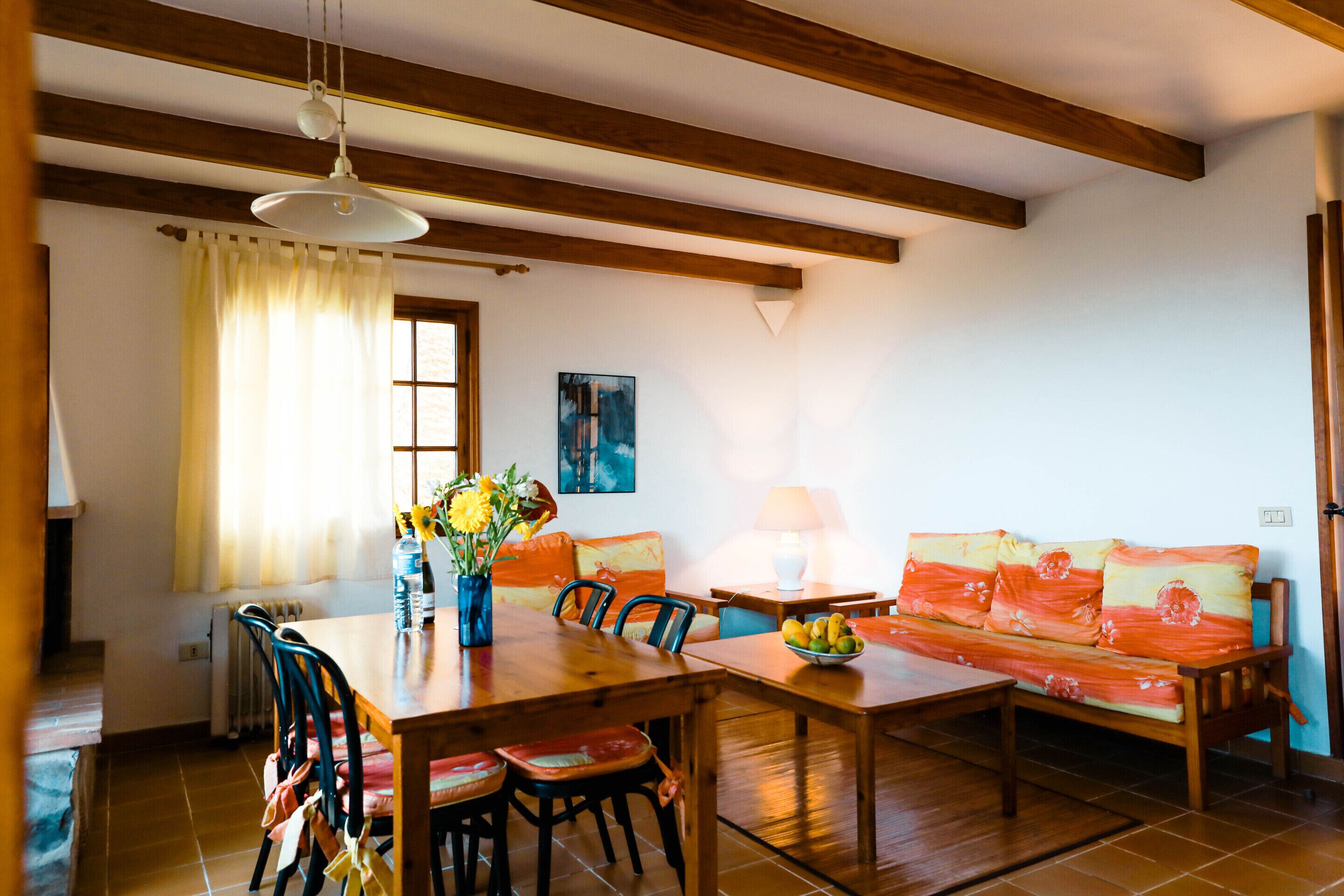 A dining area with a wooden table, chairs, a sofa, and a lamp.