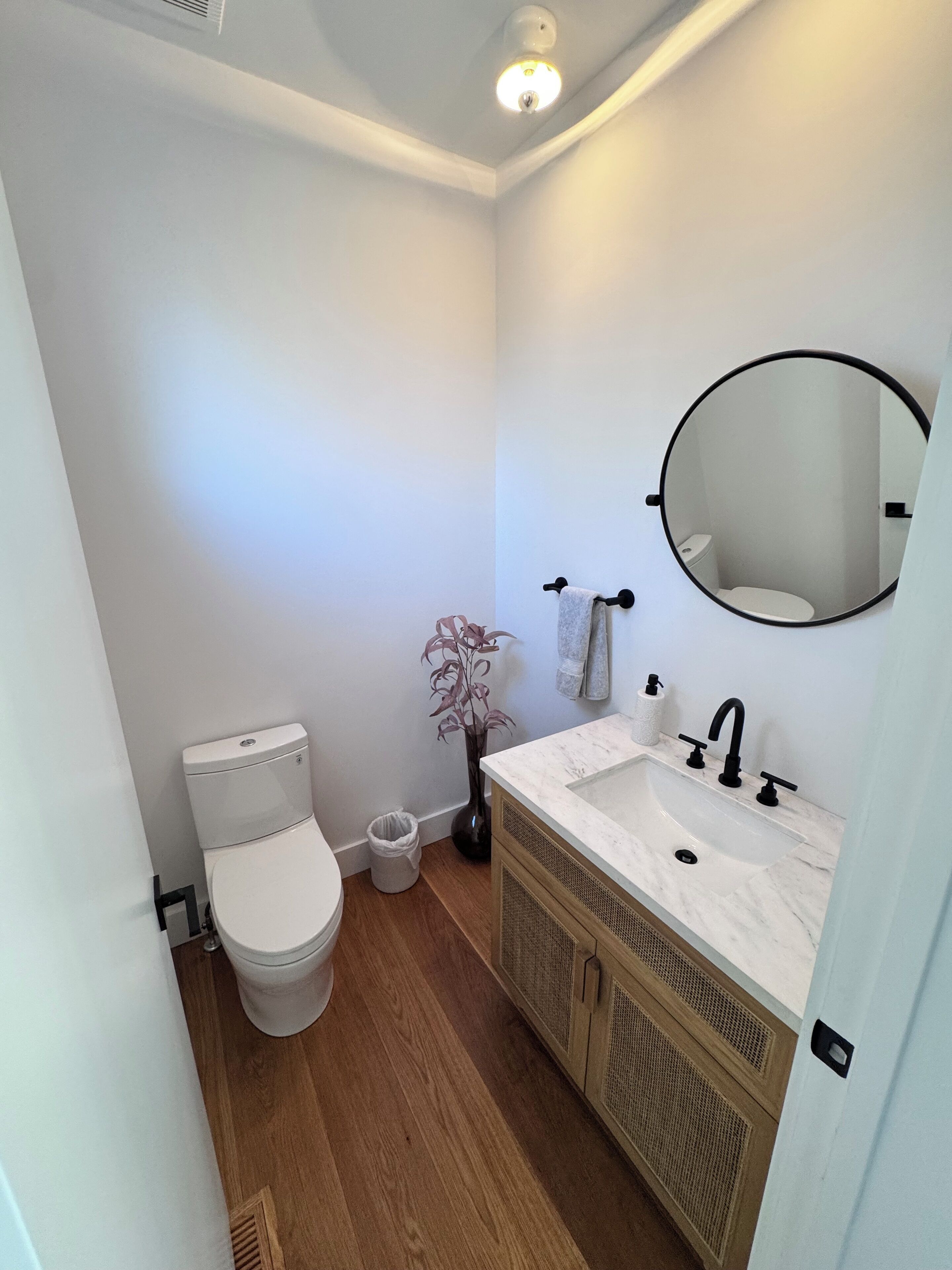 Ein Badezimmer mit Toilette, Waschbecken mit Spiegel und Blumen in einer Vase.