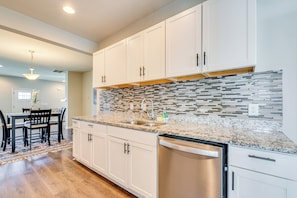 A modern kitchen with white cabinets, a granite countertop, and a stainless steel dishwasher. - Family Fun Hub: Walk to Park, 3 Mi to Dtwn Atlanta (Atlanta)