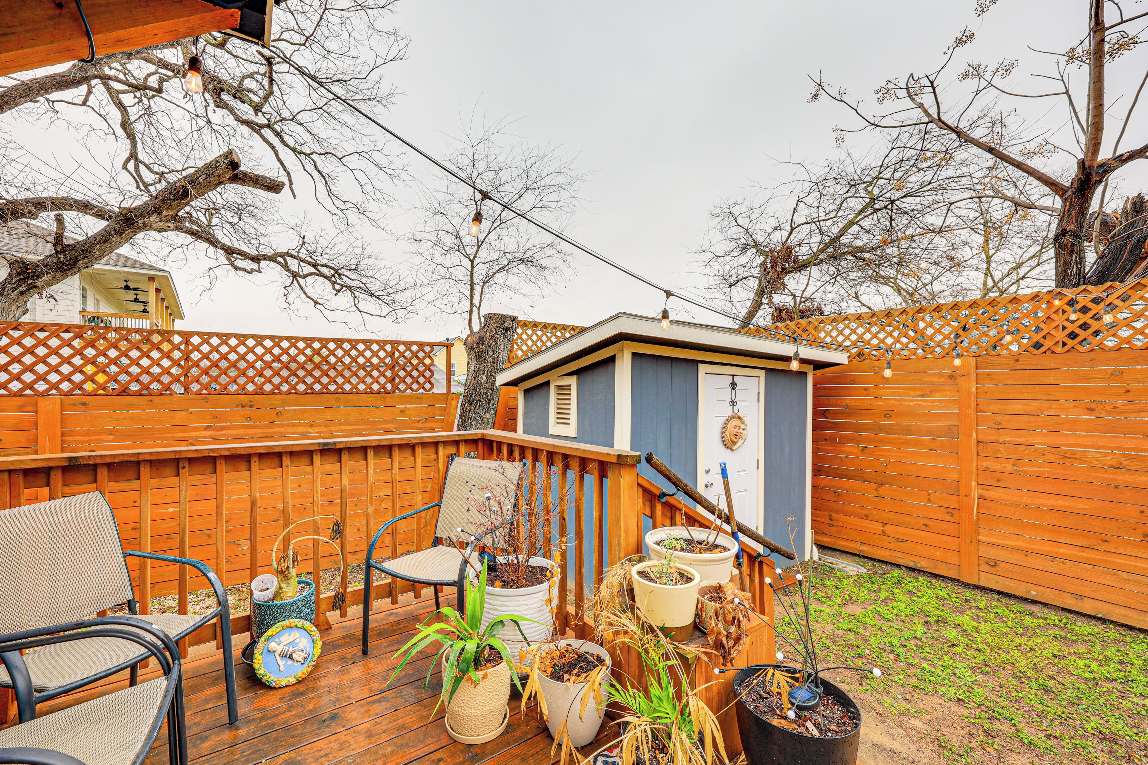 A wooden deck with potted plants, outdoor furniture, and a small shed.