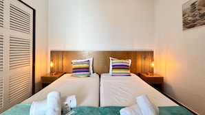 Une chambre d’hôtel avec deux lits, chacun doté d’un oreiller à rayures, d’une tête de lit en bois et de lampes de chevet.