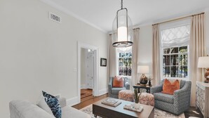 A living room with a sofa, armchair, ottoman, coffee table, and a hanging light fixture.
