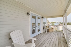 Eine überdachte Veranda mit einem weißen Sessel, einem kleinen Tisch und einer Couch.