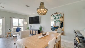 Ein modernes Wohnzimmer mit einem Holzesstisch, weißen Stühlen, einem großen Spiegel mit motivierendem Text und einer Chandelier.