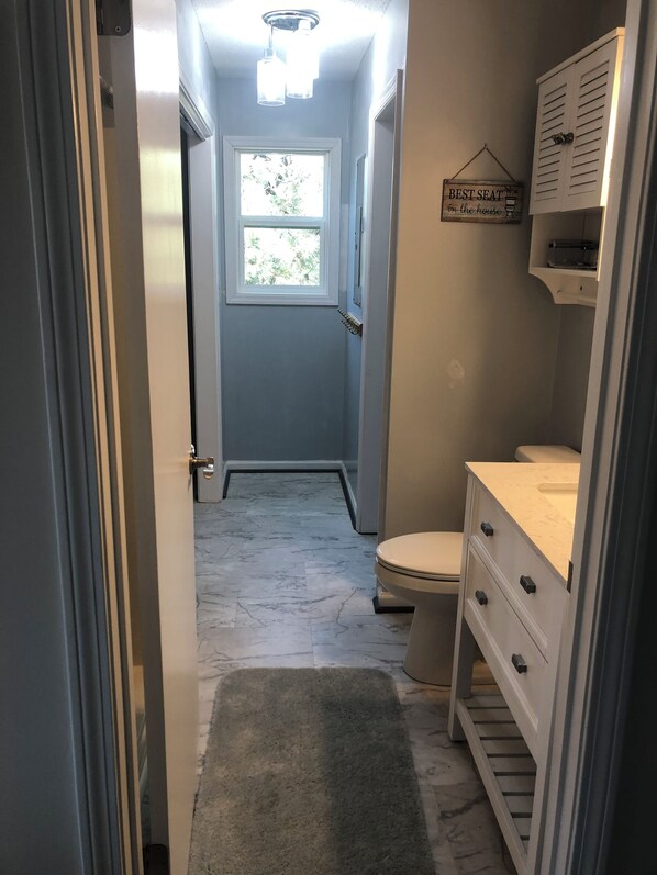 Un baño estrecho con inodoro, lavabo y zona de ducha.