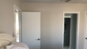 Un dormitorio con una cama, una puerta y un pasillo.