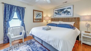 Un dormitorio con una cama grande, una silla, un ventilador de techo y dos lámparas de pared.
