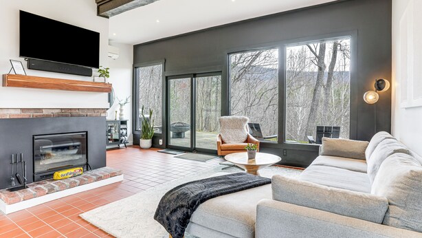 Uma sala de estar moderna com lareira, um sofá grande, uma mesa de centro e uma TV fixada na parede.