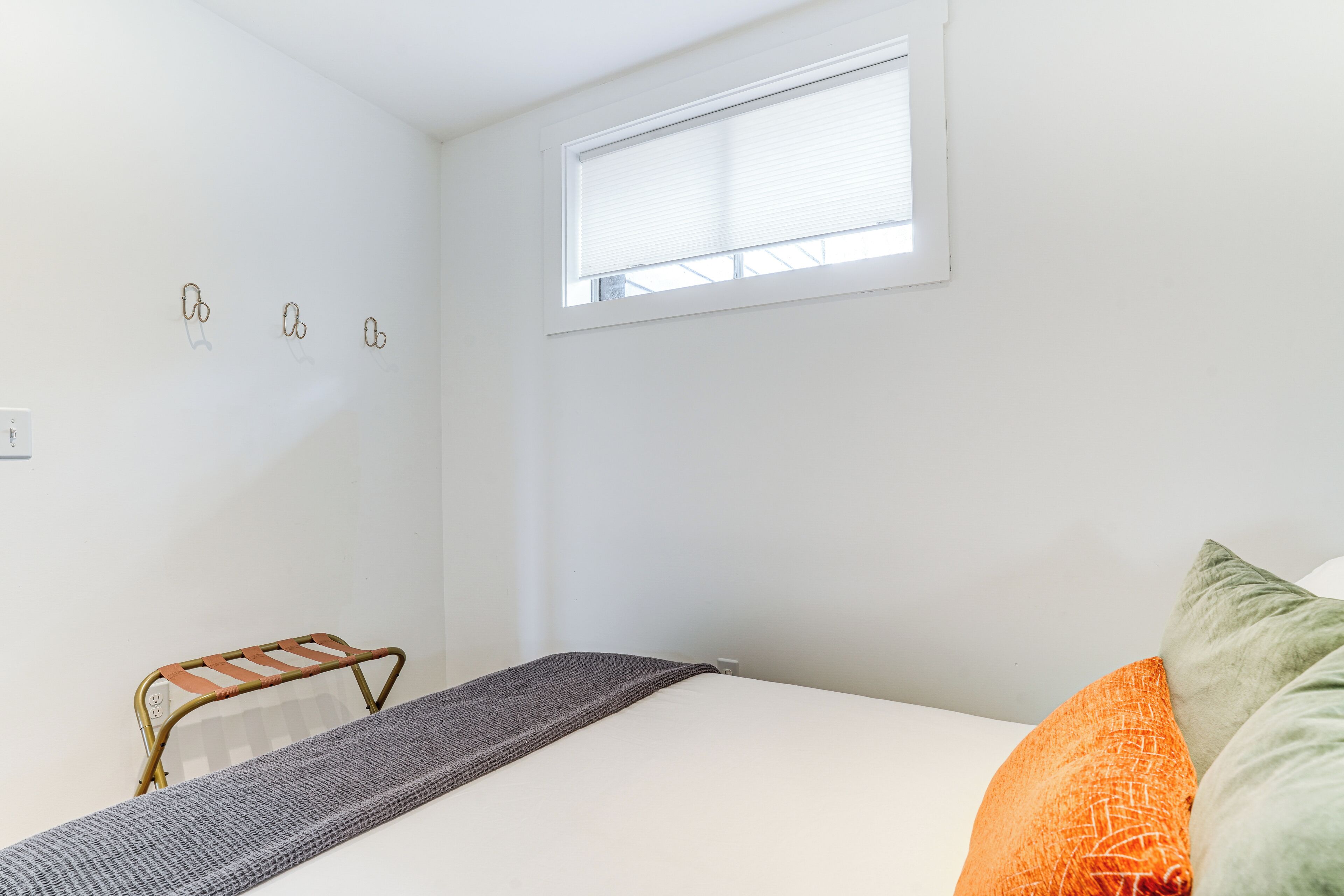 Ein kleines, sauberes Zimmer mit einem Bett, einem Fenster und einem Metallregal.